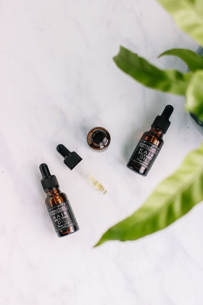 Flat lay of organic hair oil bottles with droppers on a marble surface